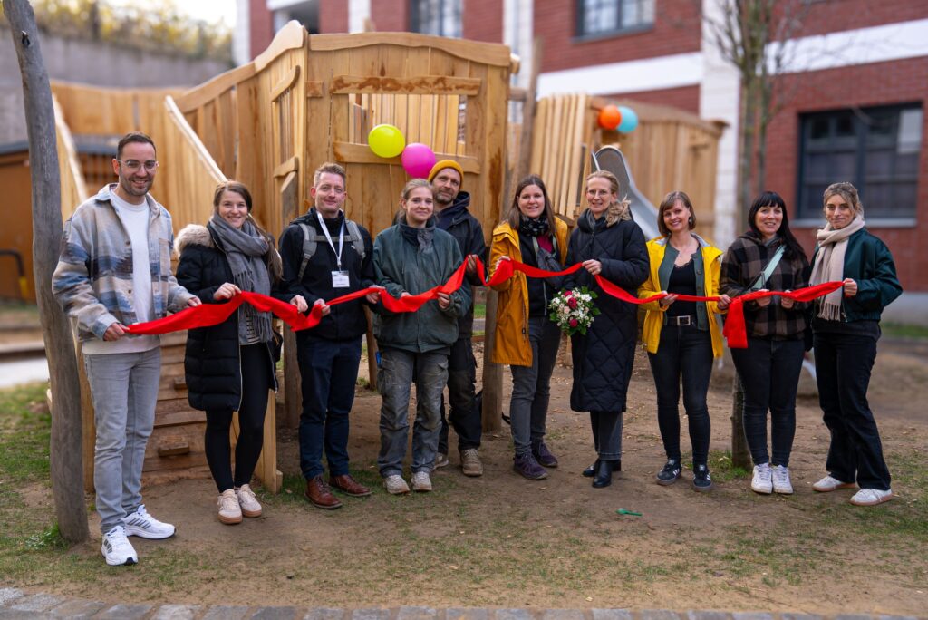 Sieben Frauen und drei Männer stehen vor dem Klettergerüst und halten ein langes rotes Band in der Hand.